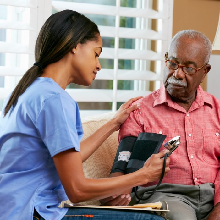 Nurse Visiting Senior Male Patient At Home Taking Blood Pressure